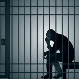 Concept of prison and arrest of an offender or criminal, with a prisoner sitting in his cell holding his head in his hands.